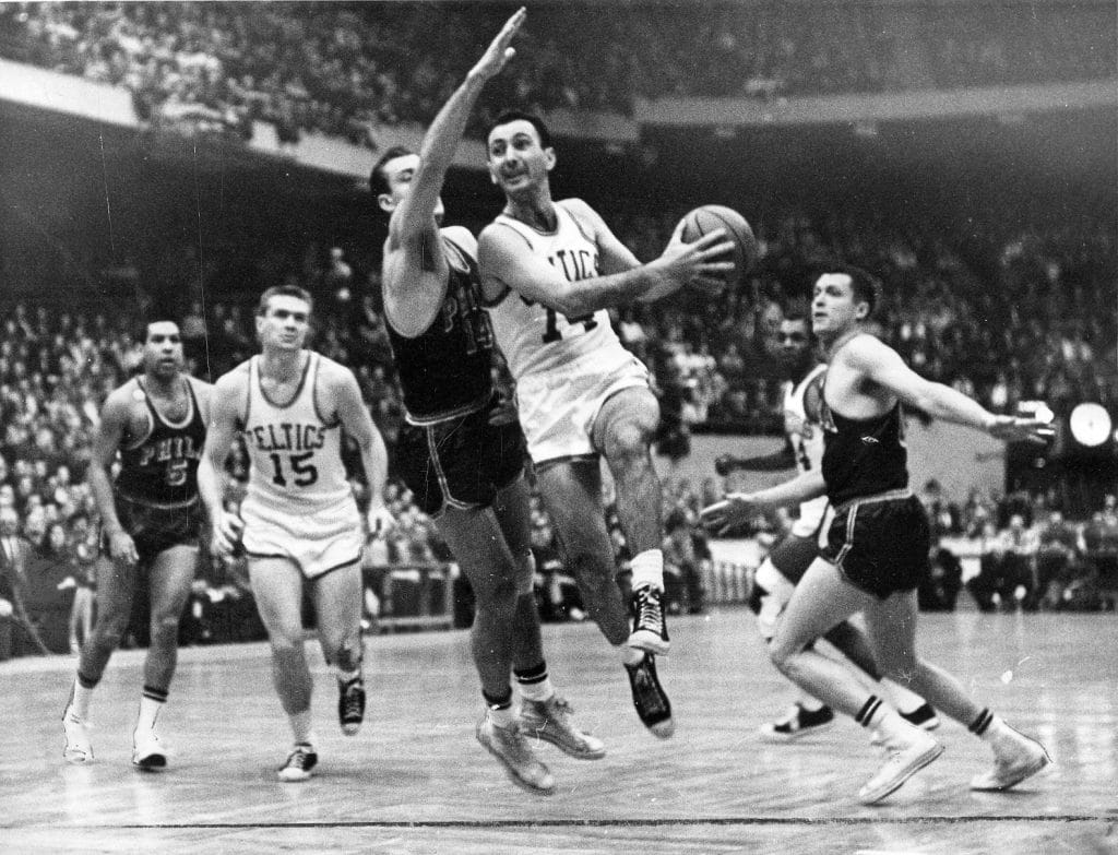 Black and white photo of Boston Celtics legend Bob Cousy driving to the basket for a layup against the Philadelphia Warriors.