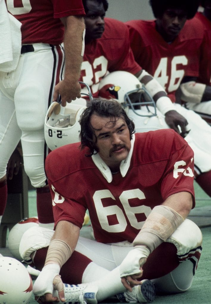Conrad Dobler, a legendary white NFL player and one of the best right guards in football history, resting on the sidelines.