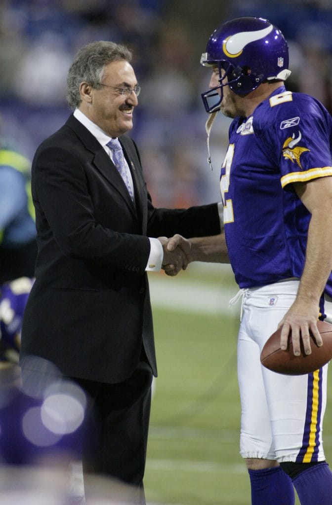 Darren Bennett, famous white football player and punter, shaking hands with owner owner Zygi Wilf before a Minnesota Vikings game.