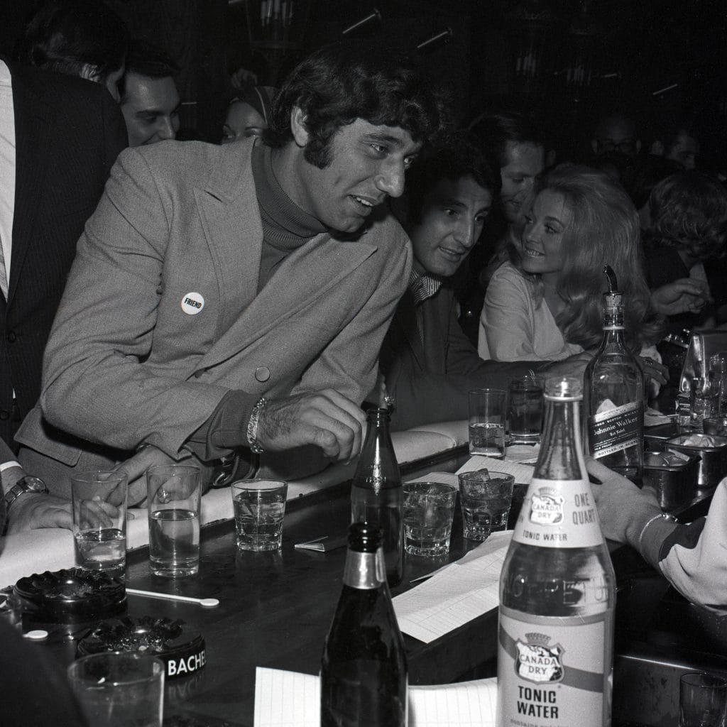 Joe Namath, a famous white NFL player, enjoying his time at a bar, embodying the swagger that made him an icon in football history.