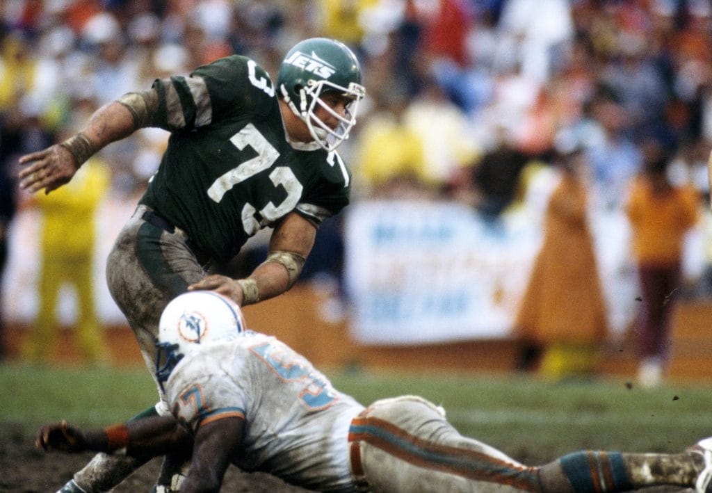 Joe Klecko powers through the Dolphins' offensive line, embodying the strength of one of the best white nose tackles of all time.