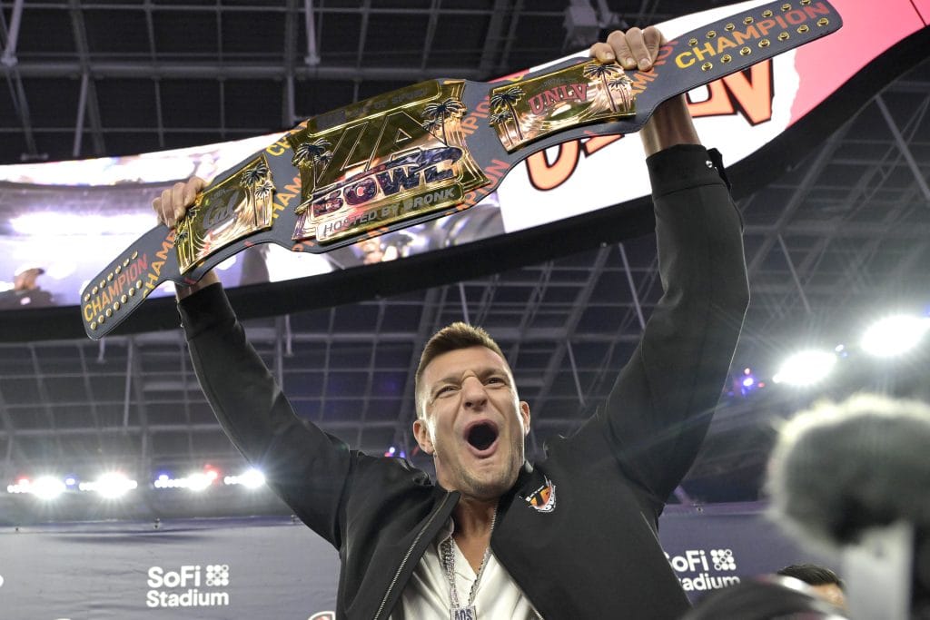 Rob Gronkowski celebrating with a championship belt, known as one of the best white football players of all time and a famous white NFL player.
