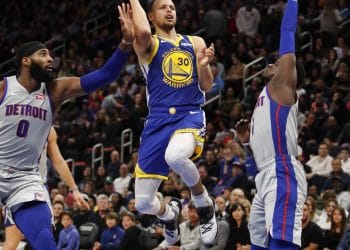 Golden State Warriors guard Stephen Curry driving through defenders for a layup against the Detroit Pistons, showcasing why he belongs among the Top 10 Point Guards of All Time.