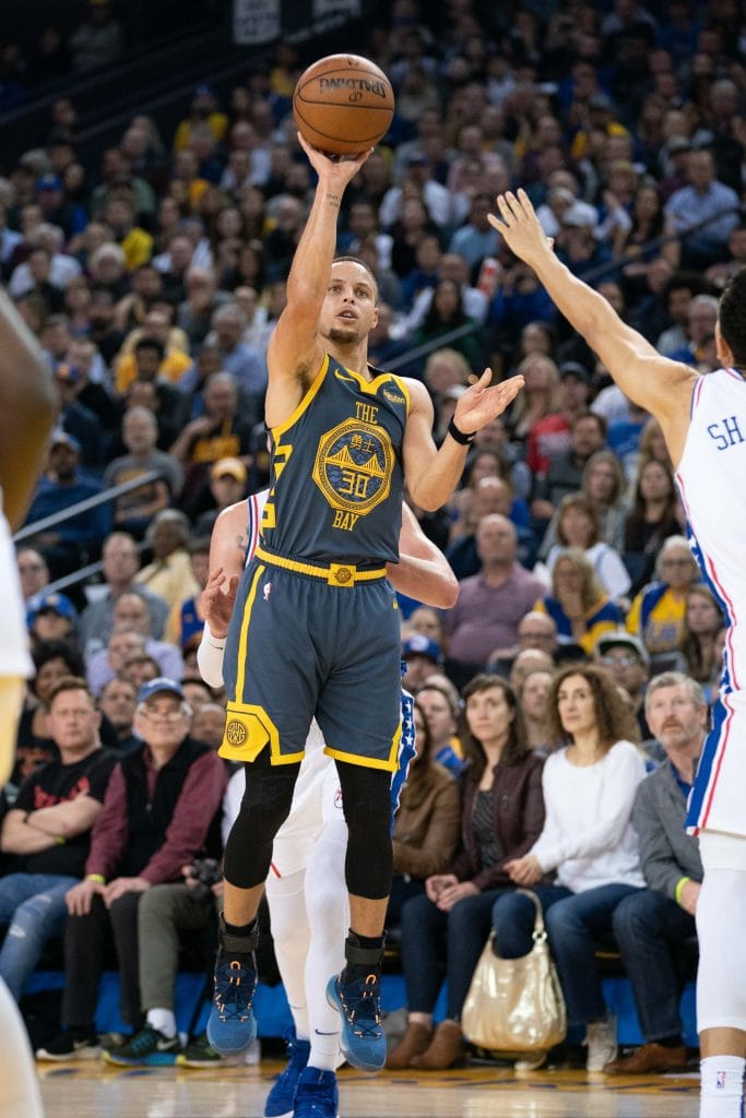 Golden State Warriors superstar Stephen Curry rising for a deep three-pointer, further cementing his legacy as one of the Top 10 Point Guards of All Time.