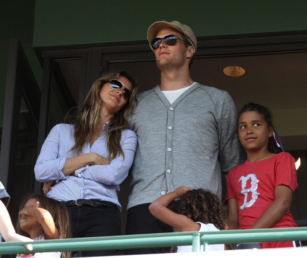 om Brady, widely regarded as the best white NFL player of all time, standing with his then-wife Gisele Bündchen at a sporting event.