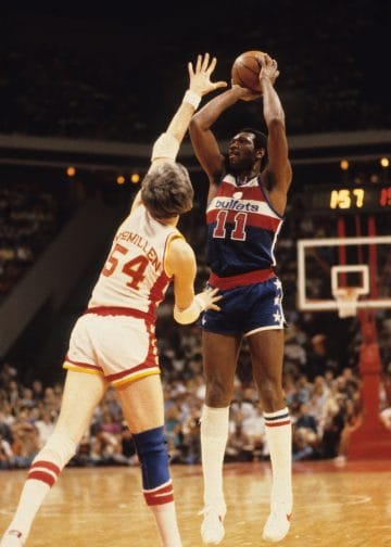 Elvin Hayes elevates for a jump shot over a Rockets defender in a Bullets uniform.