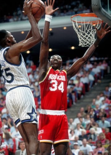 Hakeem Olajuwon gets a hand on the shot — The Dream was a defensive nightmare and sits firmly in the Top 10 NBA Defenders of All Time.
