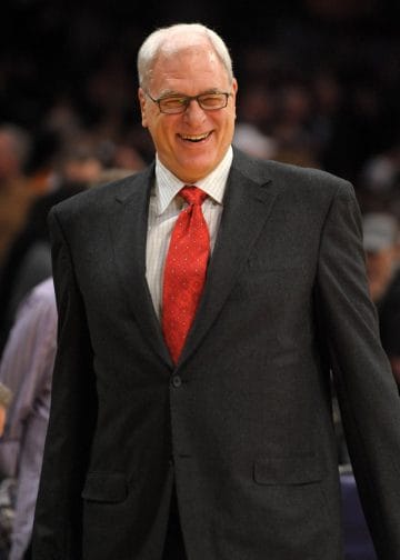 Phil Jackson smiling during a game — known for triangle offense and unmatched rings, he’s a lock for the Top 10 NBA Coaches of All Time.
