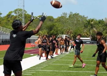 Receiver makes leaping catch over defender in intense 7v7 football action. 