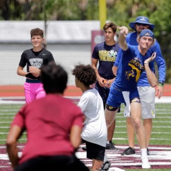 Wide receiver skies for highlight grab with defender trailing in 7v7 football