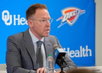 Oklahoma City Thunder GM Sam Presti speaking at a press conference with a microphone and OKC backdrop