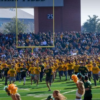 Fans storm the field in celebration during a rivalry on the baylor football schedule.
