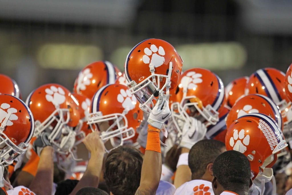 Clemson football players raise their helmets together in a pregame team huddle getting ready for the Clemson Football Schedule.