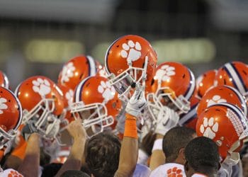 Clemson football players raise their helmets together in a pregame team huddle getting ready for the Clemson Football Schedule.