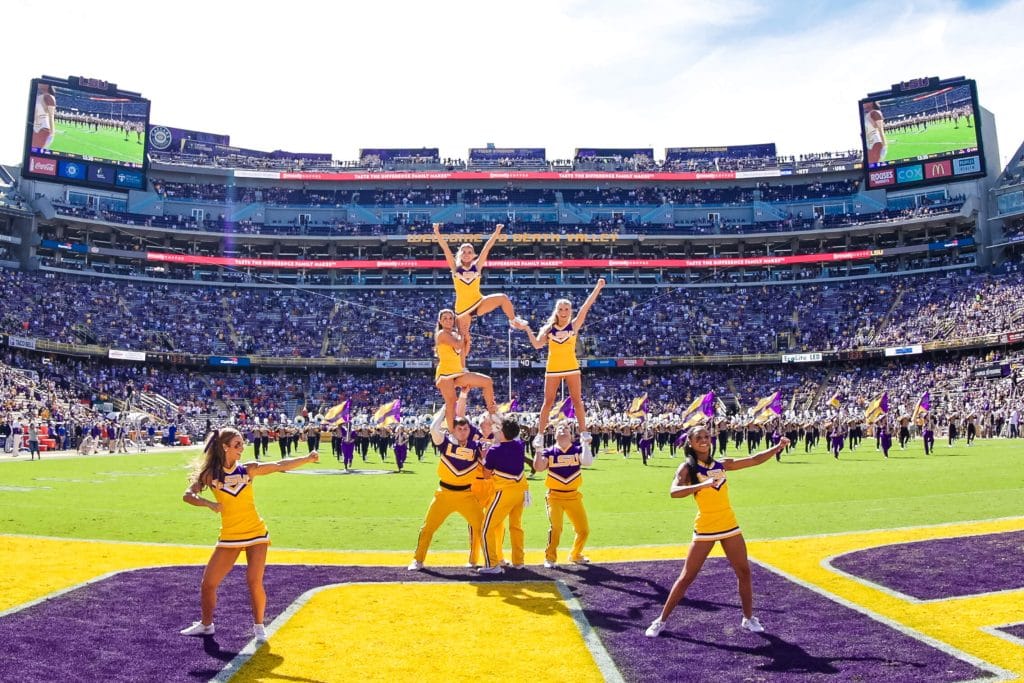 LSU cheerleaders perform on the field at Death Valley Stadium during a game day performance in front of a packed Tiger Stadium crowd.