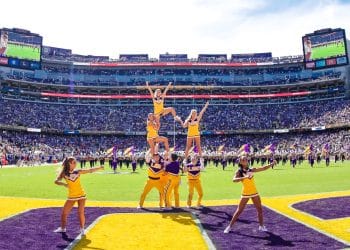 LSU cheerleaders perform on the field at Death Valley Stadium during a game day performance in front of a packed Tiger Stadium crowd.