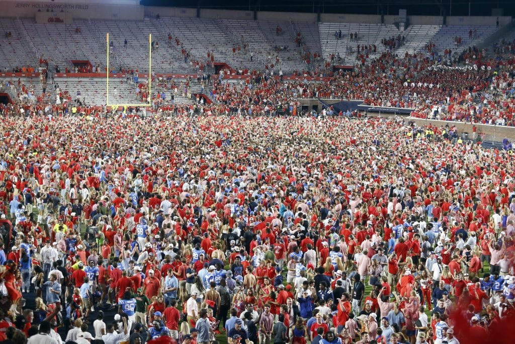 Fans storm the field at Vaught–Hemingway Stadium after Ole Miss victory, capturing the electric atmosphere in Oxford.