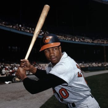 Black baseball player Frank Robinson posing with a bat in his Baltimore Orioles uniform. 