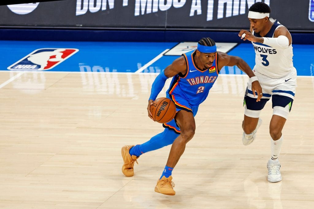 Shai Gilgeous-Alexander drives past a Timberwolves defender in an Oklahoma City Thunder home game.