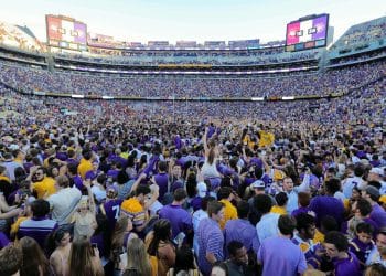 LSU fans storm the field at Death Valley Stadium after a big win, celebrating with packed stands and a sea of purple and gold.