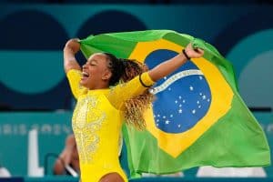 Rebeca Andrade celebrating with the Brazilian flag after winning a historic team medal at the Paris 2024 Olympics