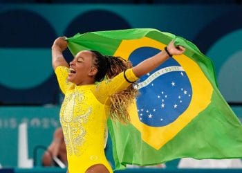 Rebeca Andrade celebrating with the Brazilian flag after winning a historic team medal at the Paris 2024 Olympics