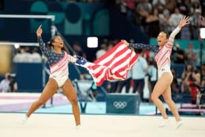 ordan Chiles and Sunisa Lee of Team USA celebrating with the American flag after winning team gold at the Artistic Gymnastics Olympics in Paris 2024