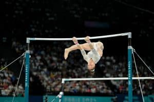 Kaylia Nemour mid-routine on the uneven bars during her gold medal performance representing Algeria at the 2024 Paris Olympics